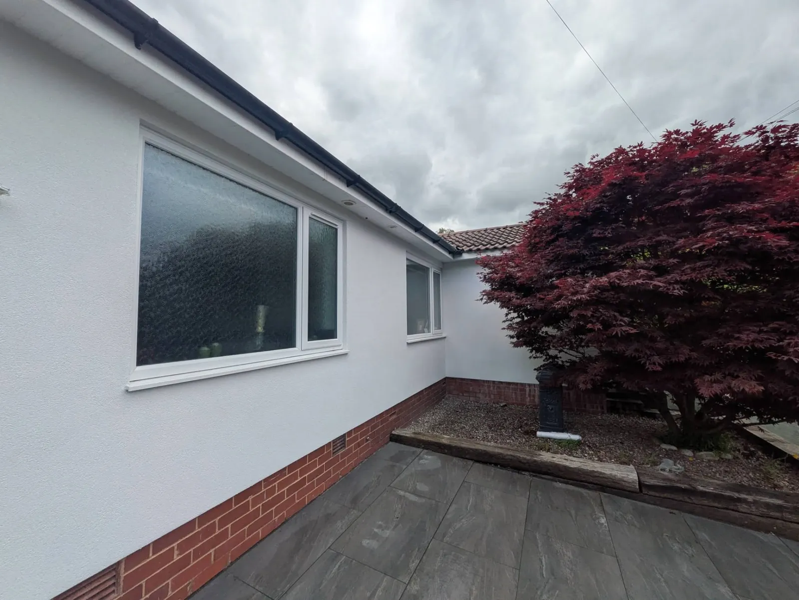 White rendered bungalow exterior with brick plinth