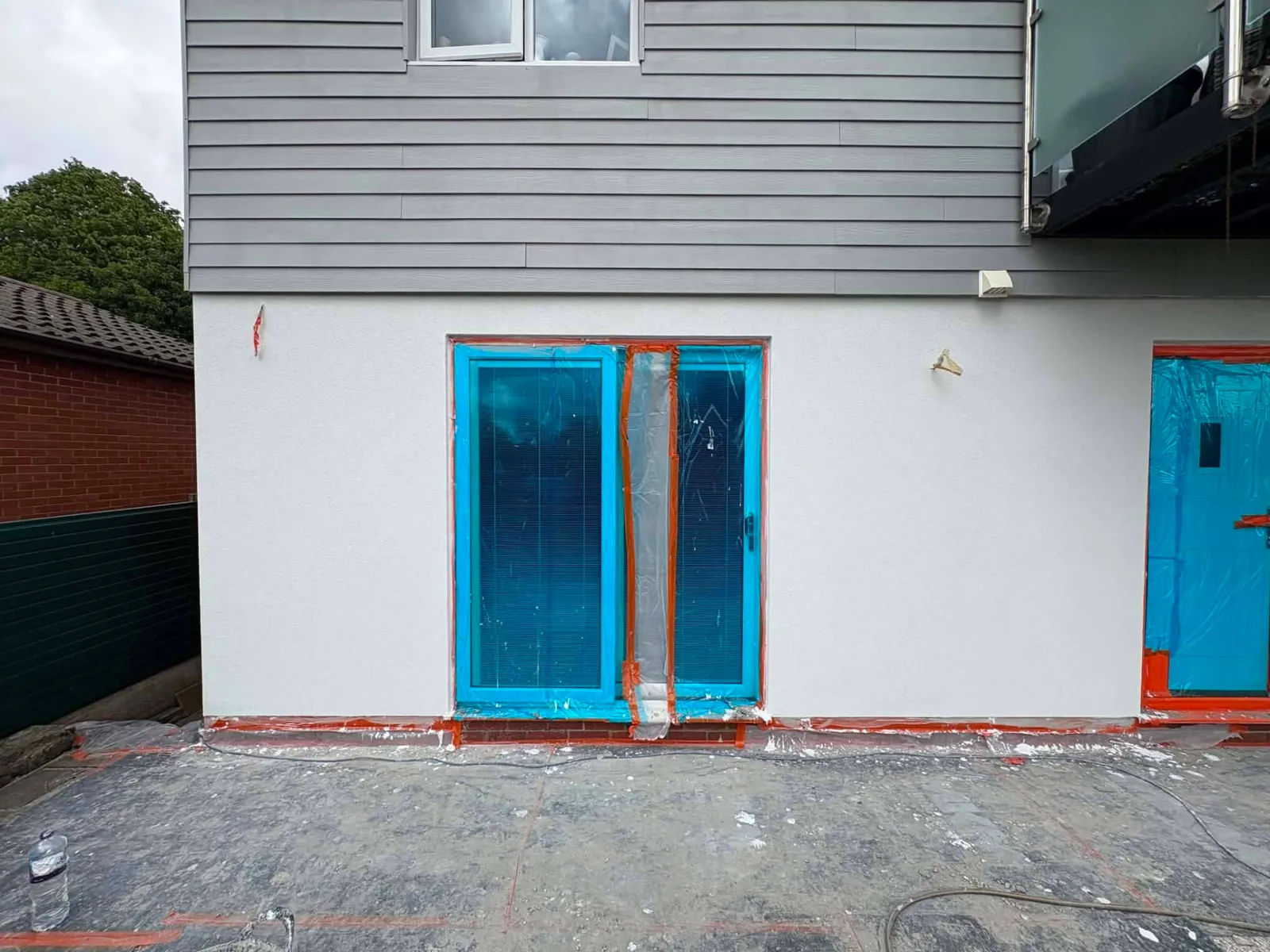 Fresh render on a house rear with doors protected by film