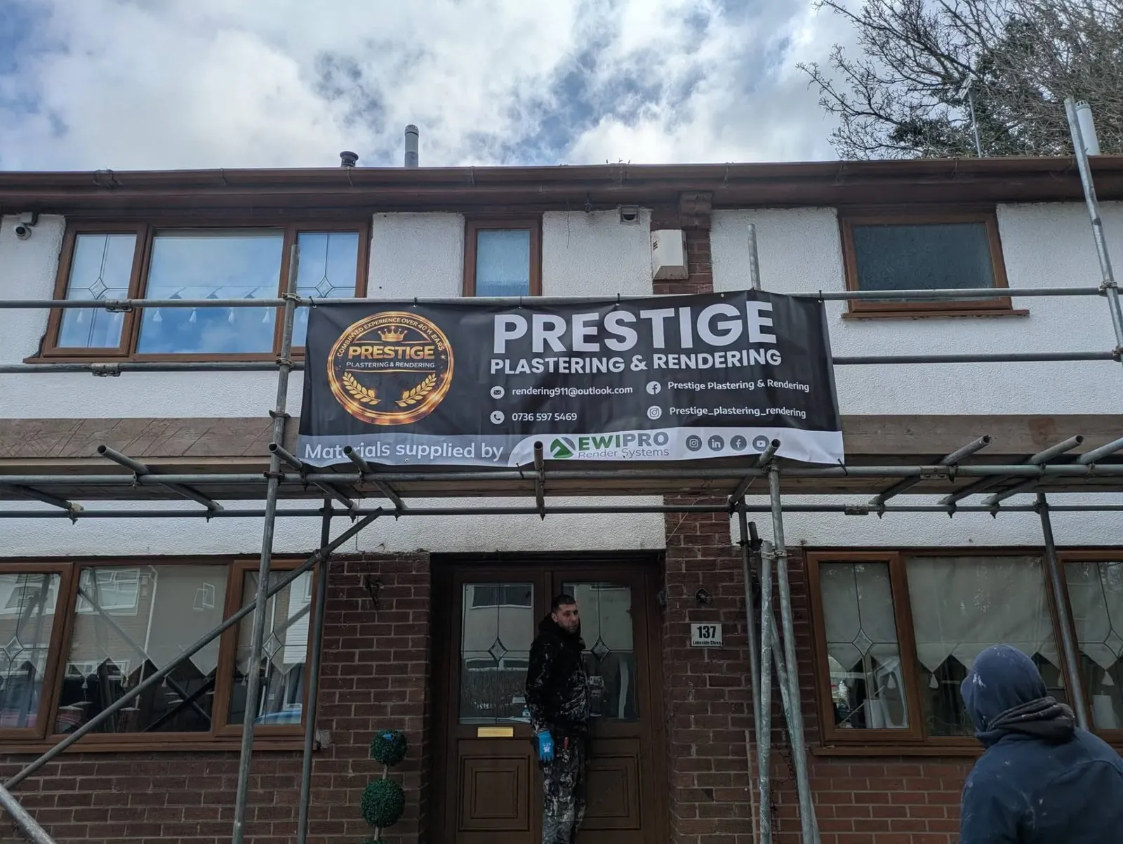 The Prestige team on scaffolding during a rendering project, with the company banner displayed